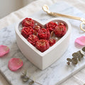 Blooming Heart candle by House of Wick  red hand-sculpted roses with gold glitter in a white heart-shaped eco resin bowl