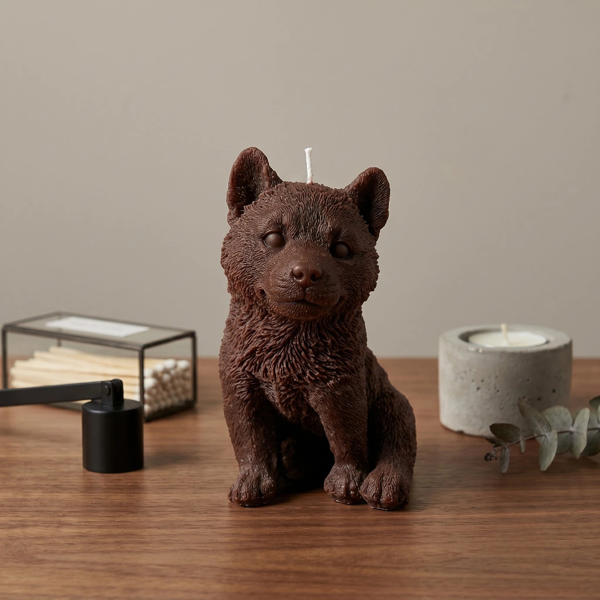 Chocolate brown husky puppy candle on a wood desk as sculptural home decor.