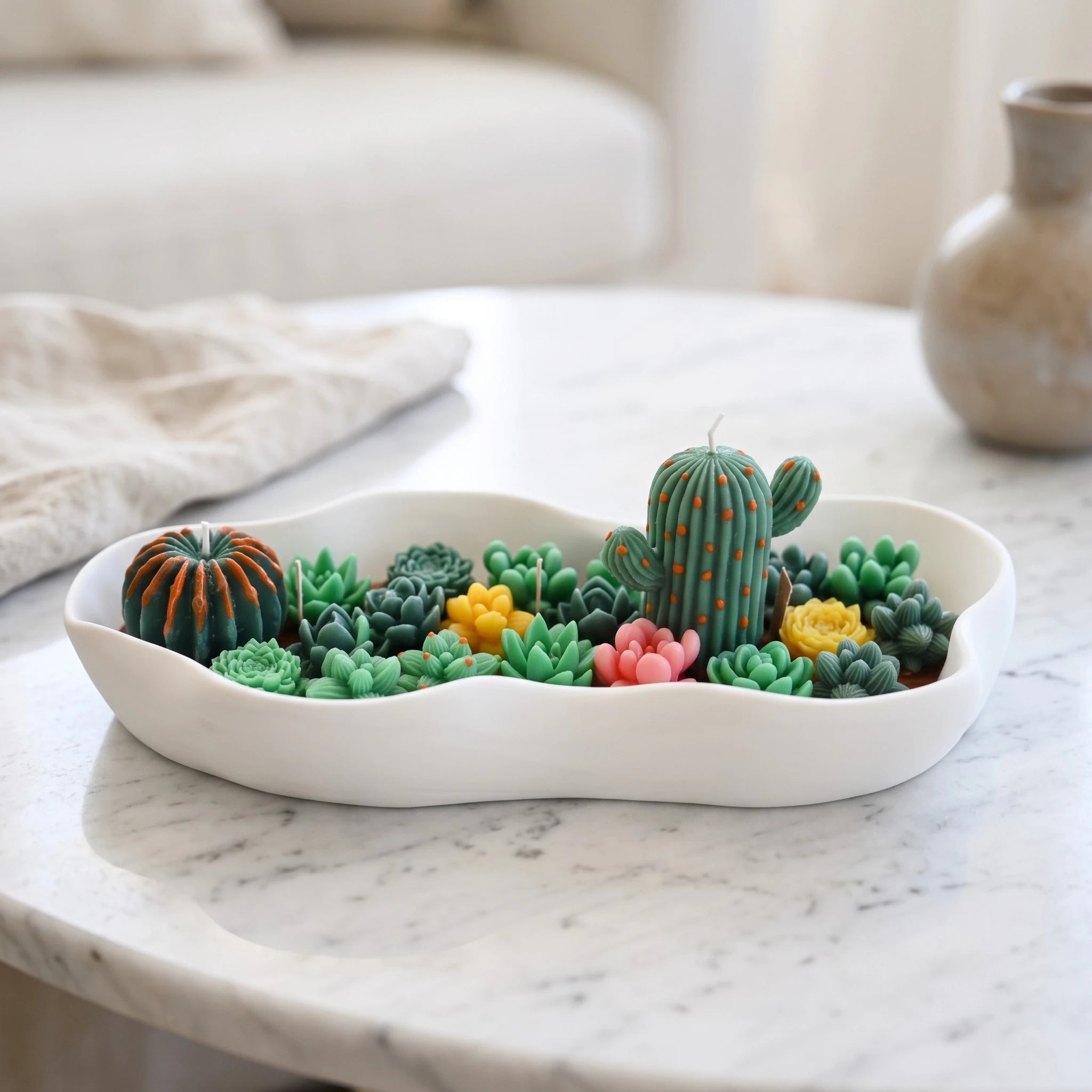 The Desert Oasis succulent candle by House of Wick — hand-sculpted green succulents and a cactus in a white irregular eco resin bowl on a marble table