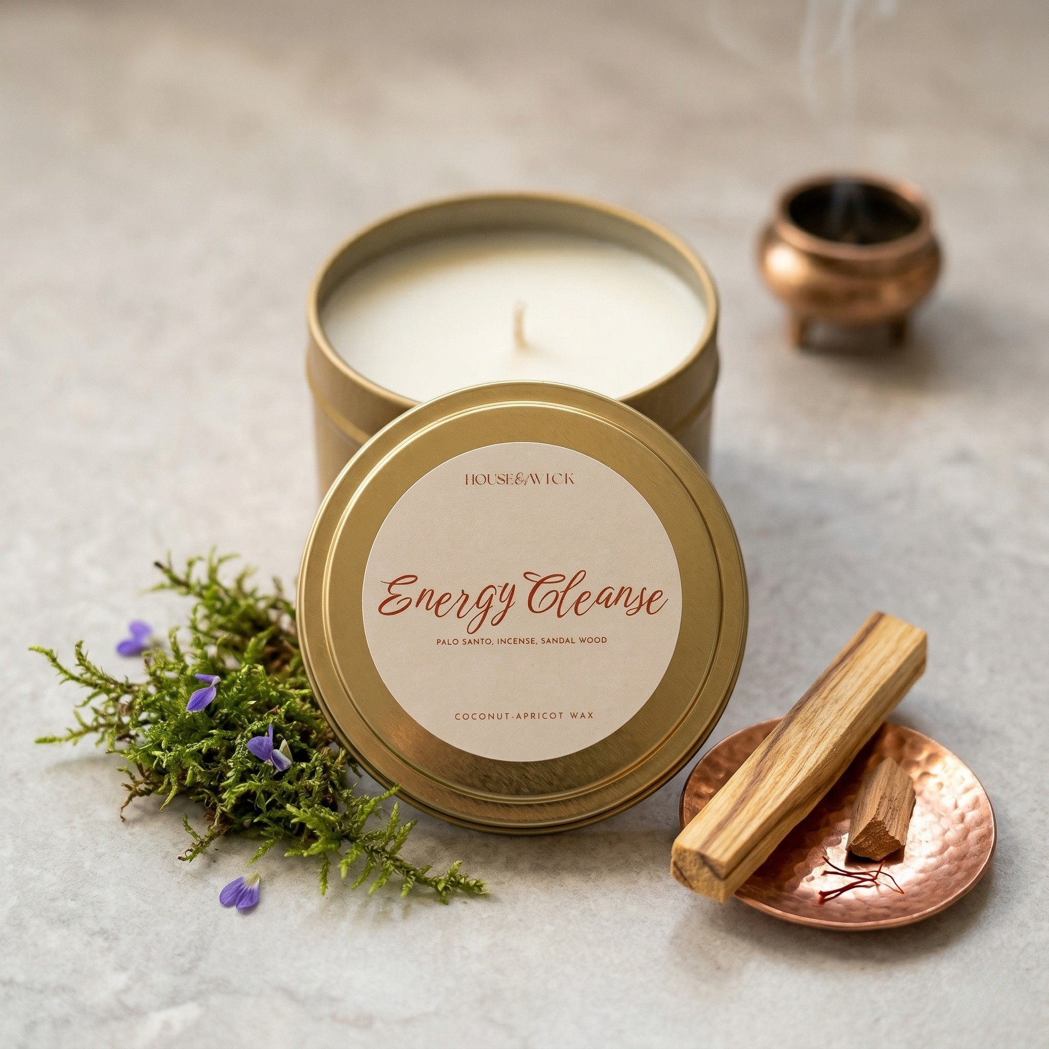 House of Wick Energy Cleanse 6oz black tin candle next to Palo Santo wood sticks.