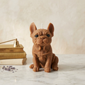 brown french bulldog candle on a marble surface with books and lavender flowers in the background