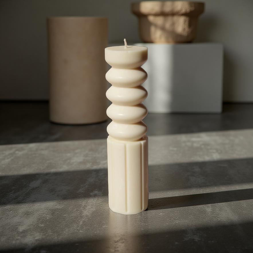 Ripple Pillar sculptural soy wax candle by House of Wick in neutral ivory, modern architectural pillar design displayed on a stone surface with soft natural lighting.