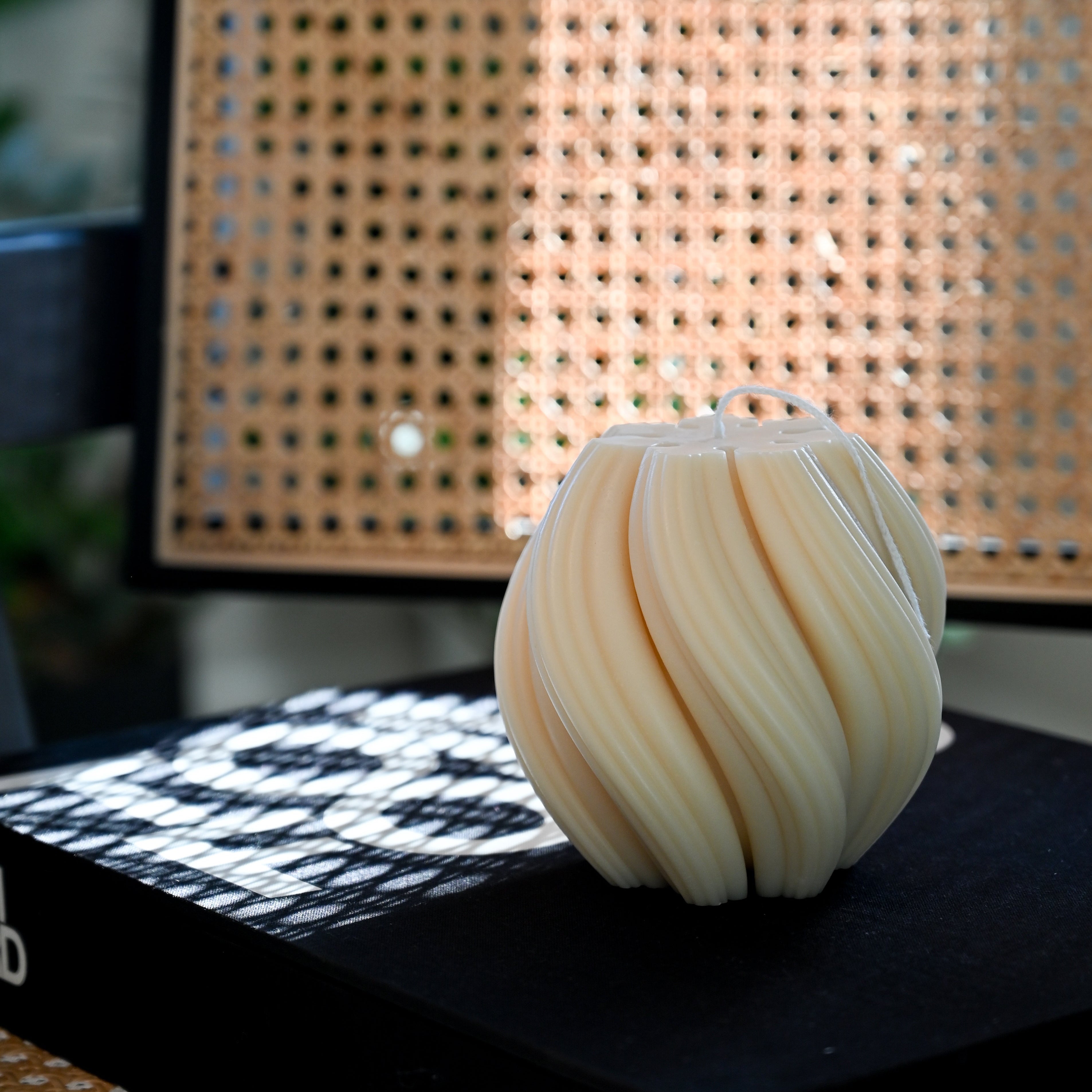 Neutral swirl candle styled as modern home decor accent with textured background showcasing handmade sculptural candle design.
