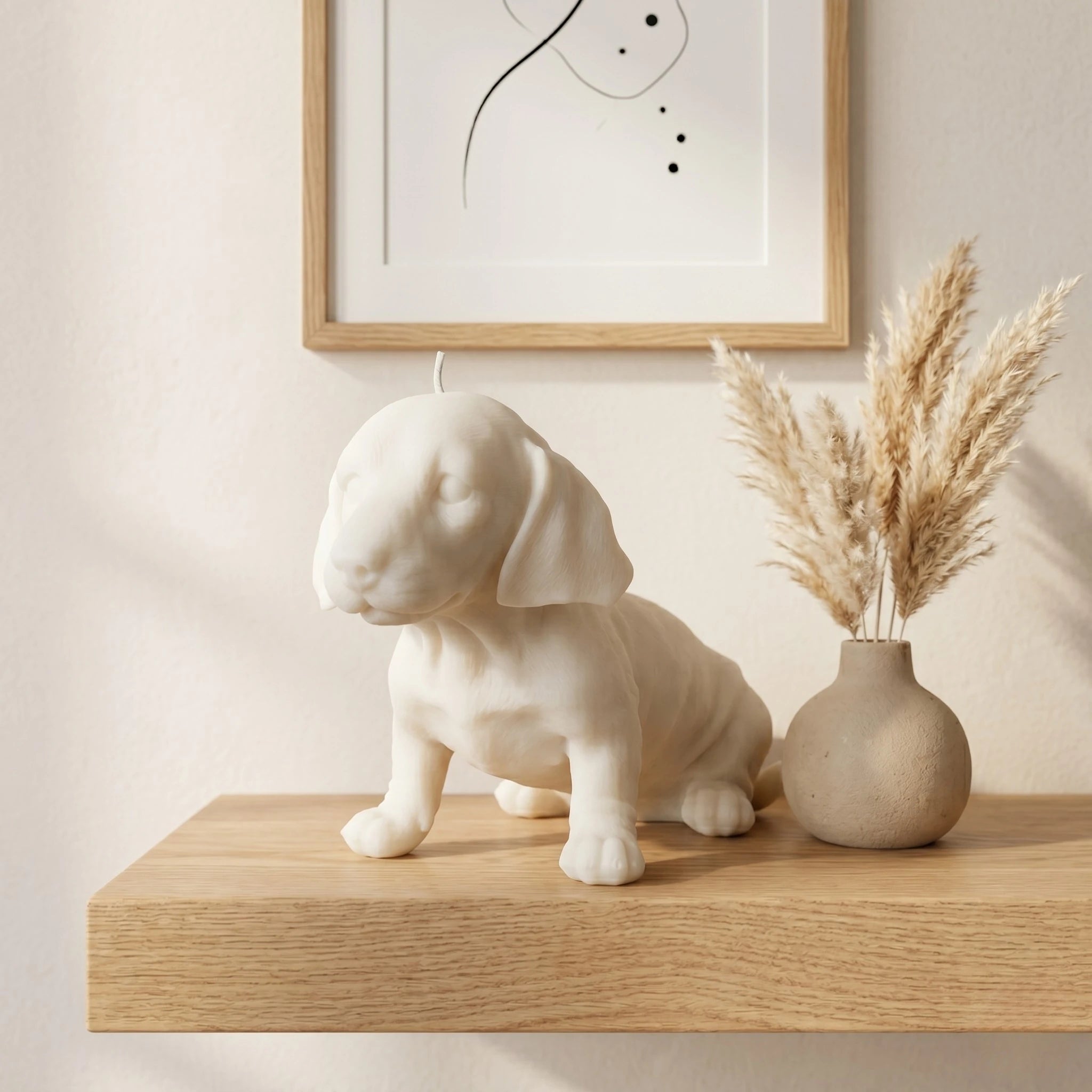 White dachshund puppy candle lifestyle on shelf with art and pampas grass