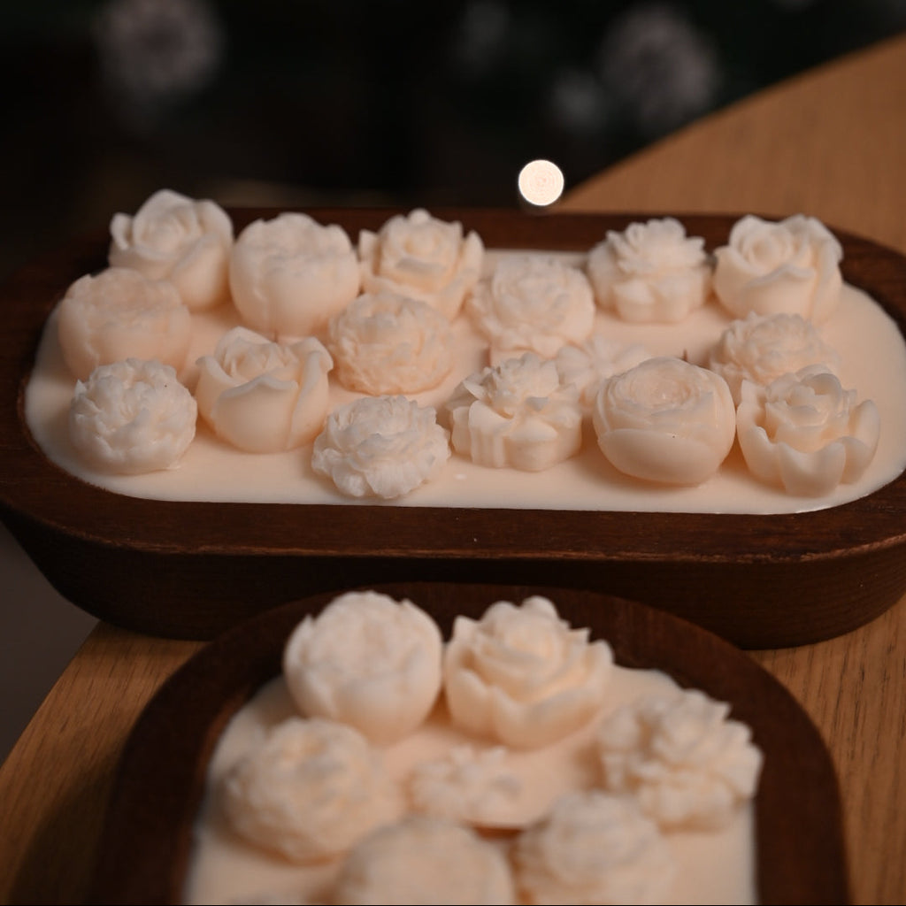 Collection of handmade floral soy candles in rustic wooden bowls arranged for decorative home styling.