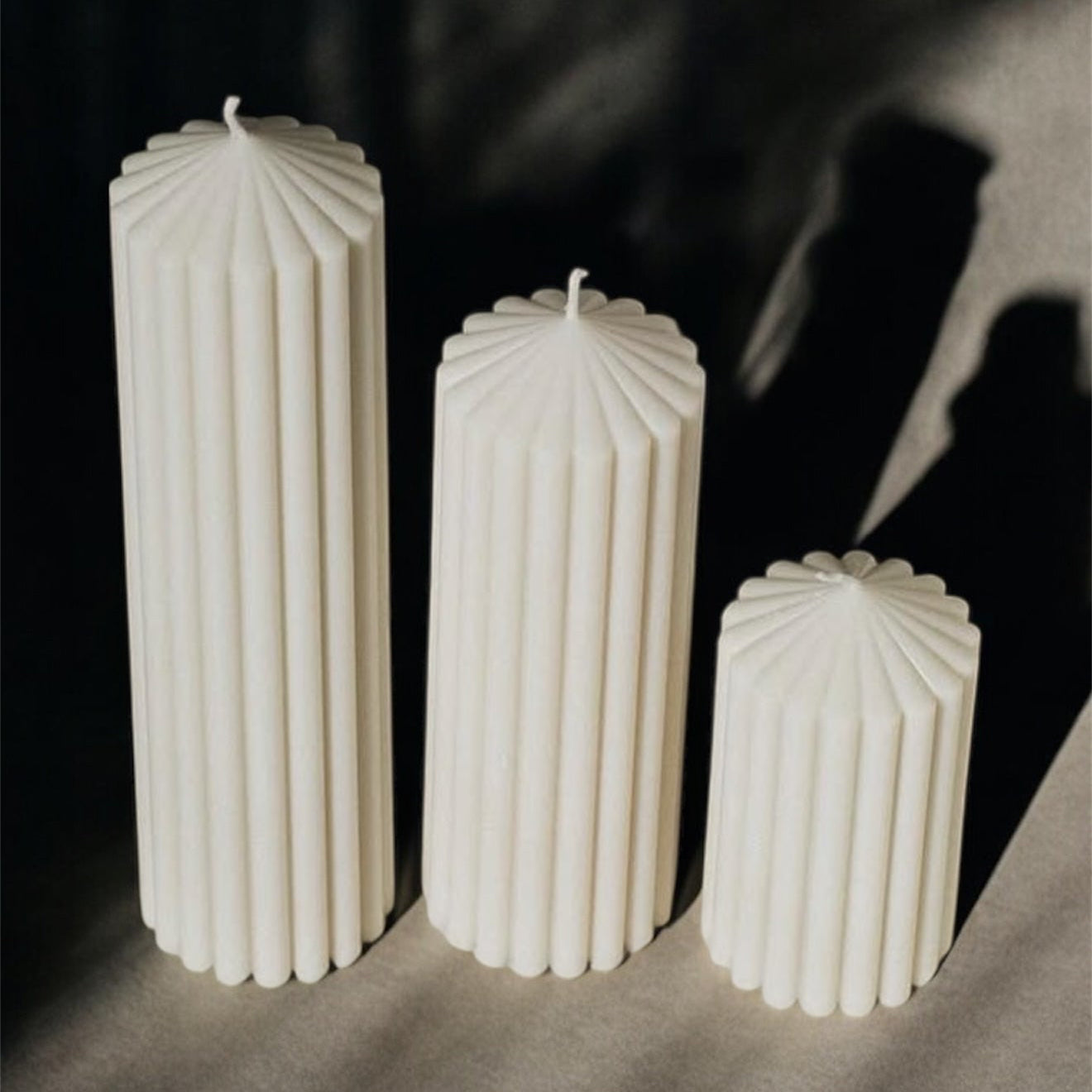 Ribbed pillar candle set in neutral soy wax displayed in a moody modern setting highlighting sculptural texture and minimalist home decor styling.
