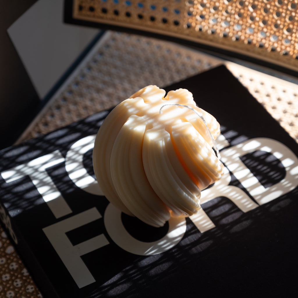 Sculptural swirl candle casting soft shadows in warm lighting, modern decorative soy wax candle for minimalist home decor.
