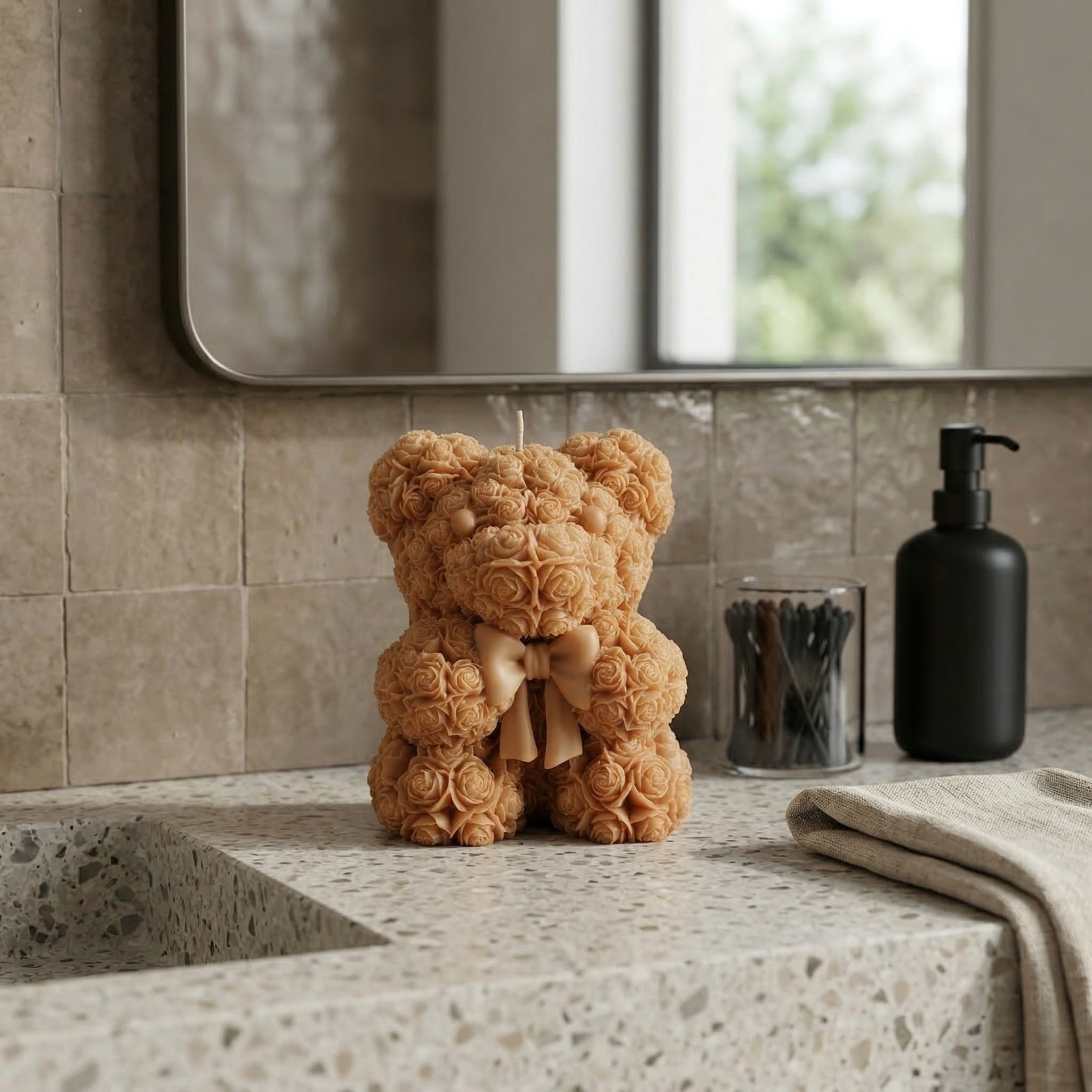 Beige teddy bear candle with bow placed on a bathroom counter with soft neutral aesthetic styling