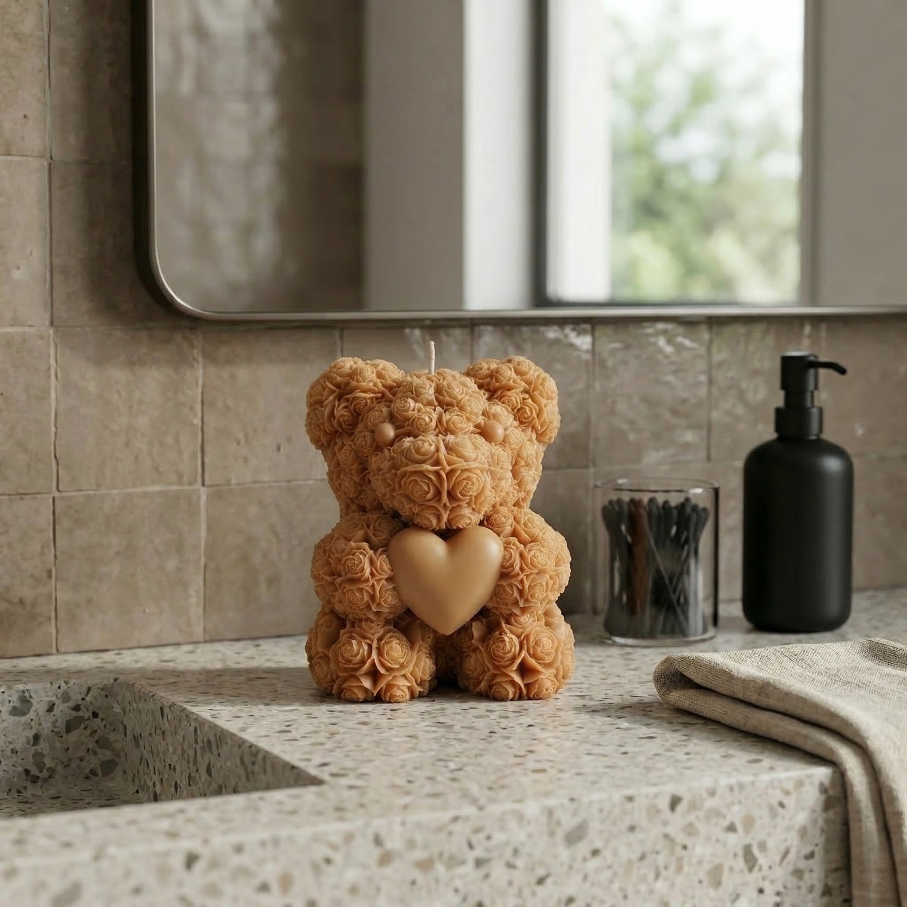 Beige teddy bear candle with heart styled on a bathroom countertop with modern spa-like decor