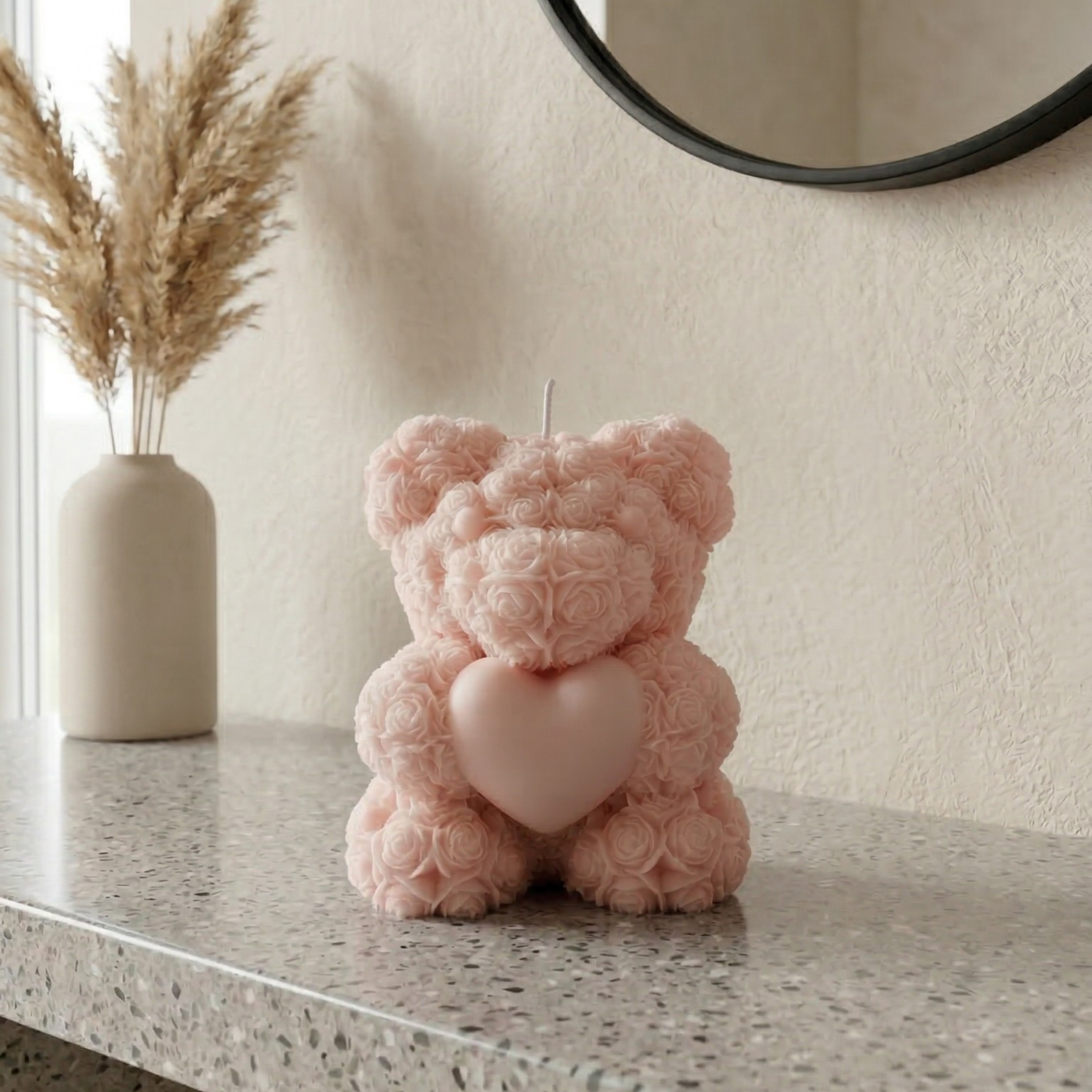 Light pink teddy bear candle with heart placed on a console table with neutral modern decor
